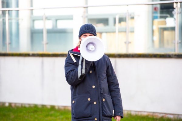 A man standing outside with a megaphone to his mouth.