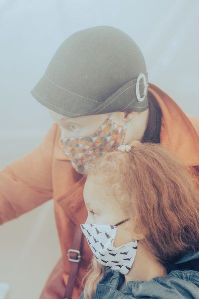 A mother and daughter wearing masks looking to the left in a pod with simulated pollution