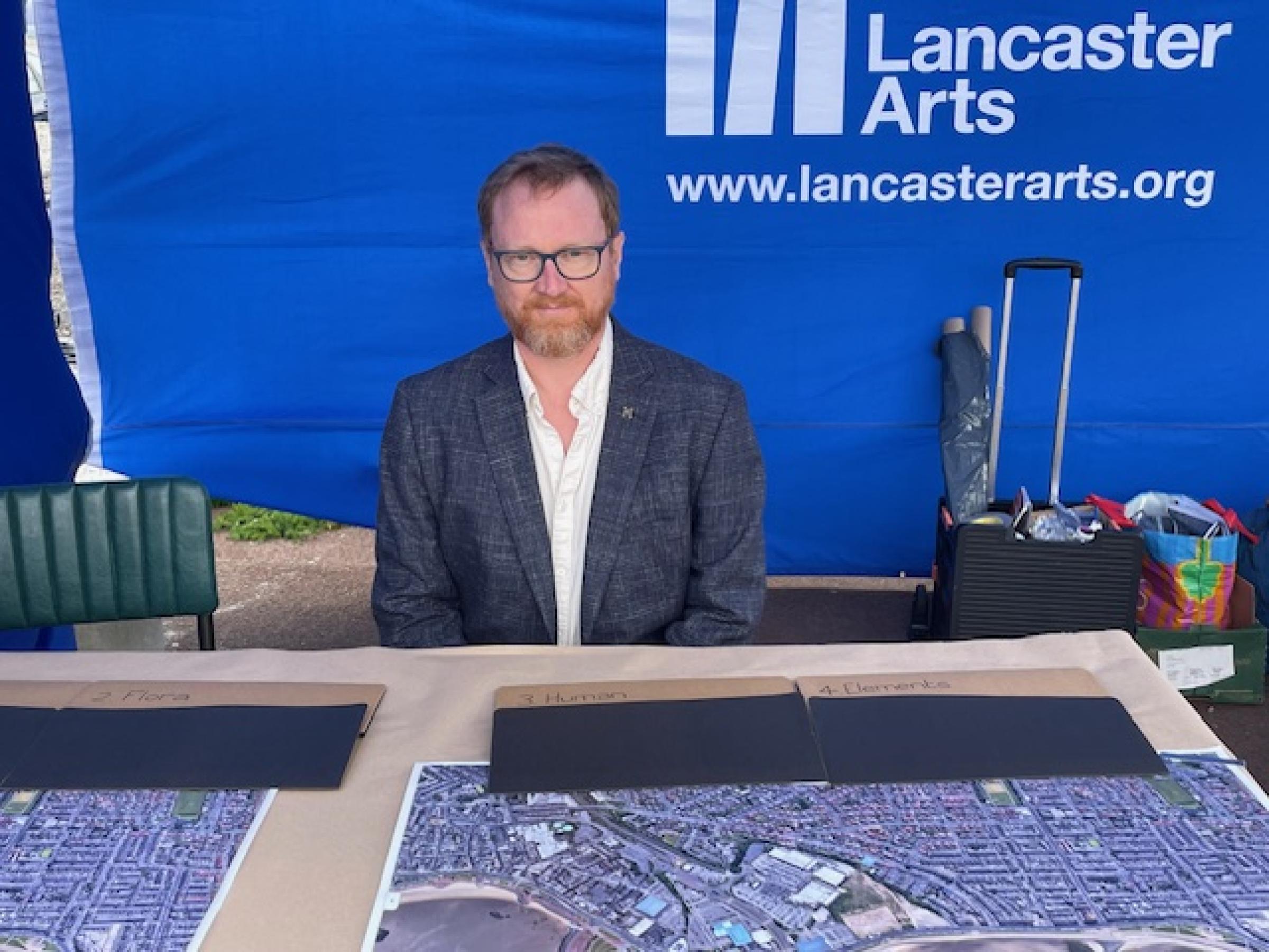 A man sitting behind a table with a map on it