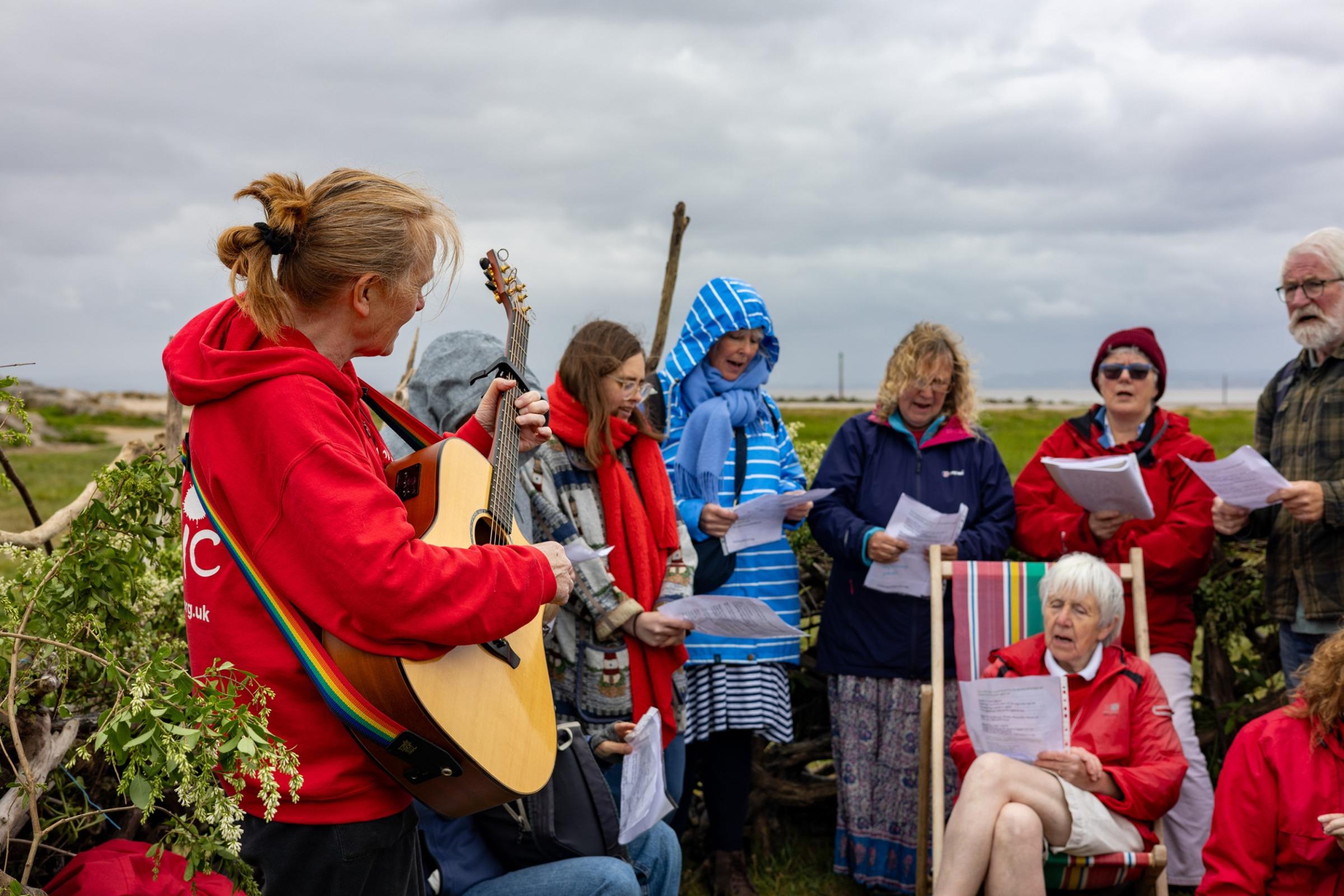 A group of people singing in a human sized nest on a beach