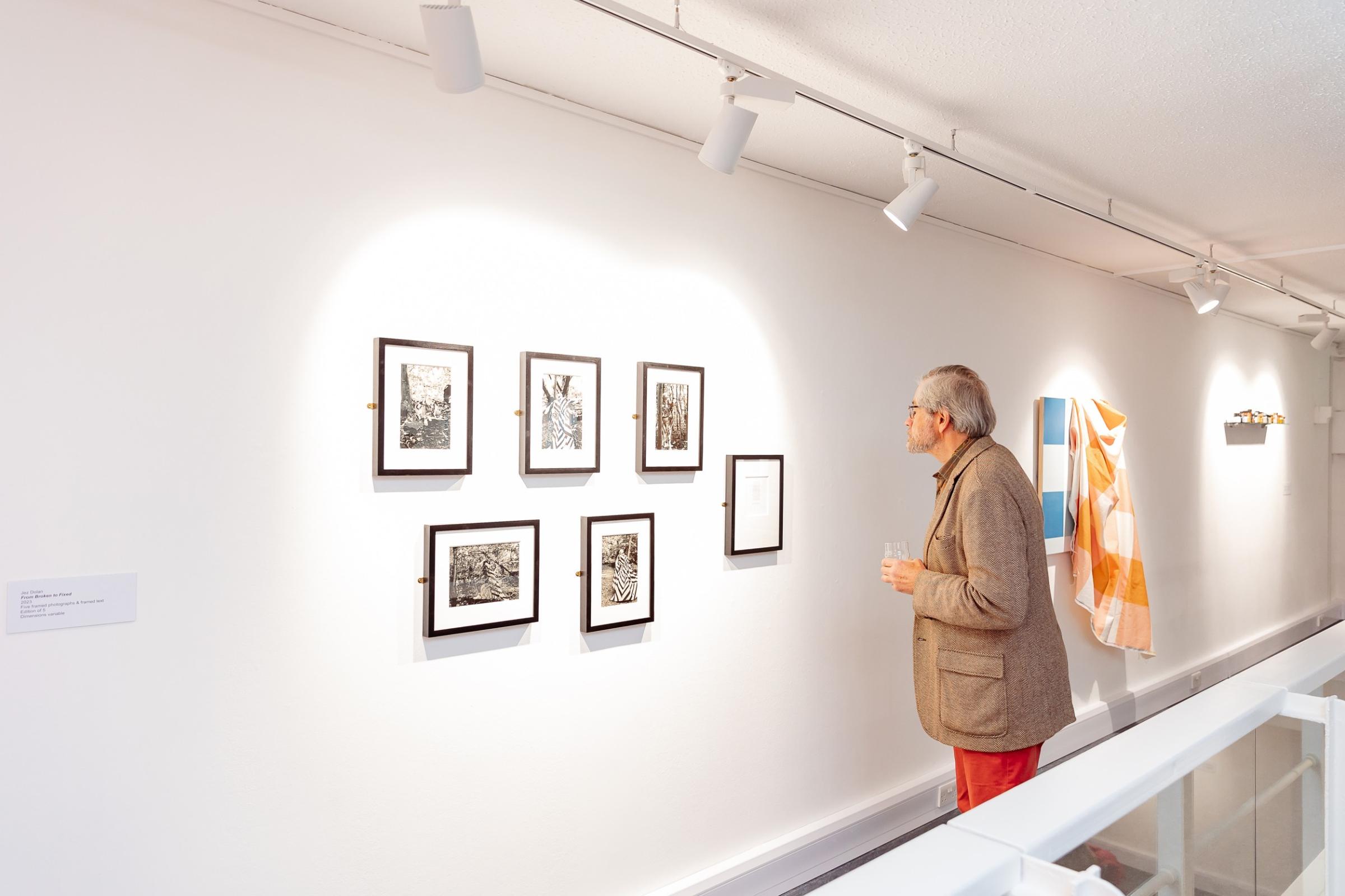 a man looking at artworks on a gallery wall
