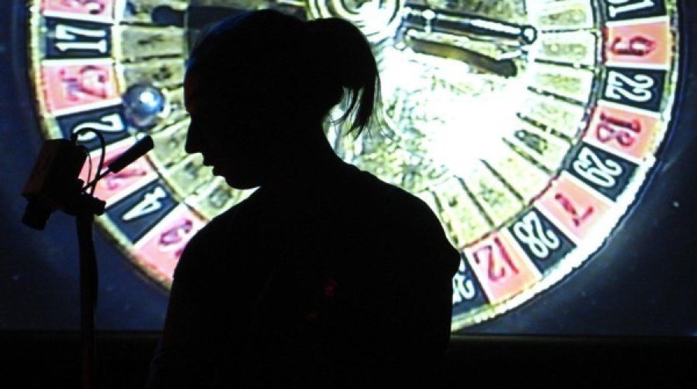 A female performer standing in front of a projection of a roulette wheel