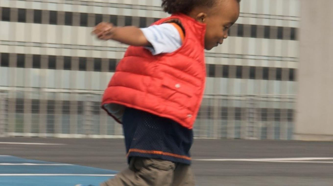 A toddler with a red gilet jacket running