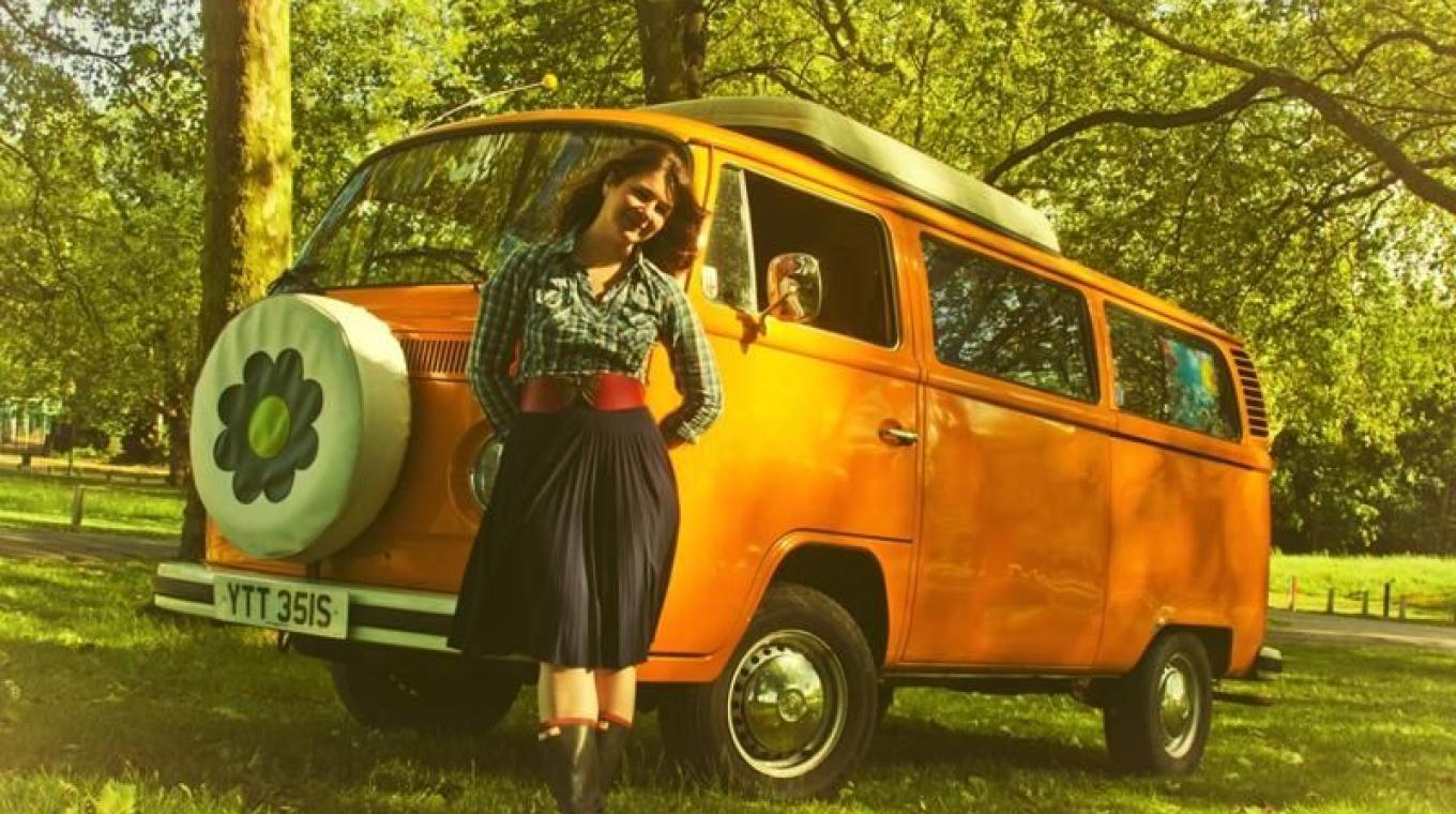 Performer stood in front of a static VW camper van in-between trees