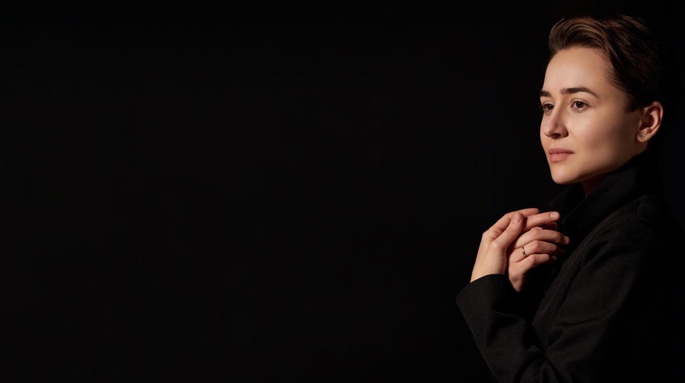 A woman with hands her chest looking to the side