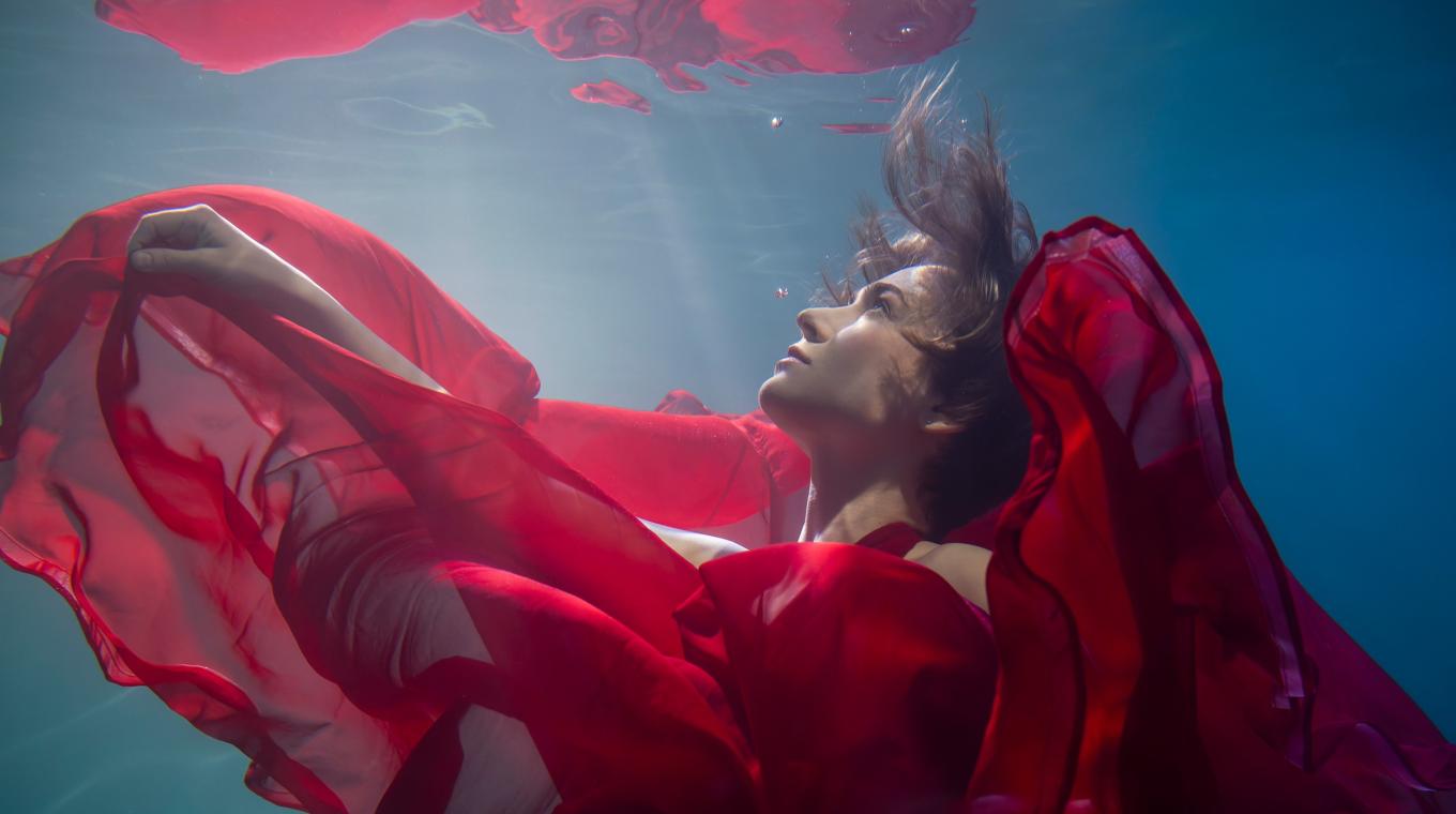 A woman in a red dress underwater