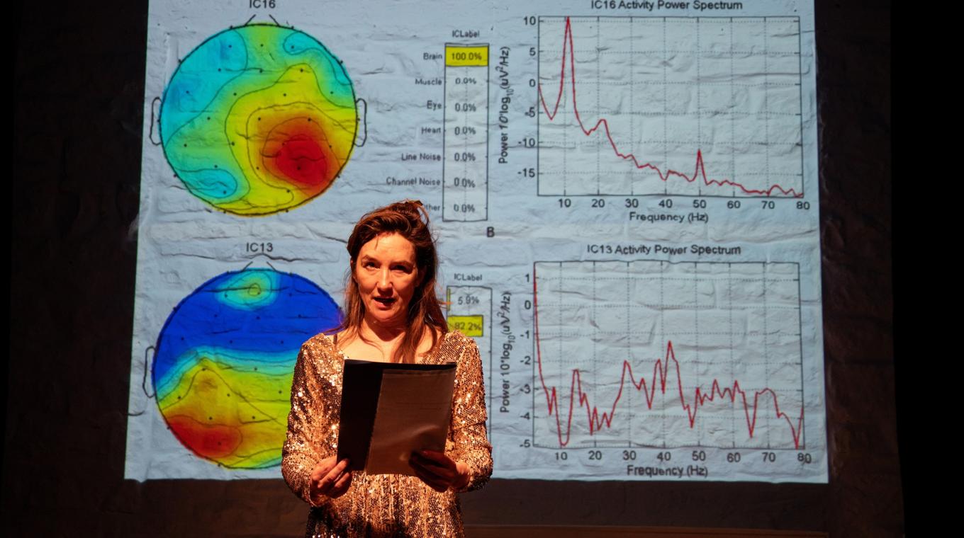 A woman with charts on a screen behind