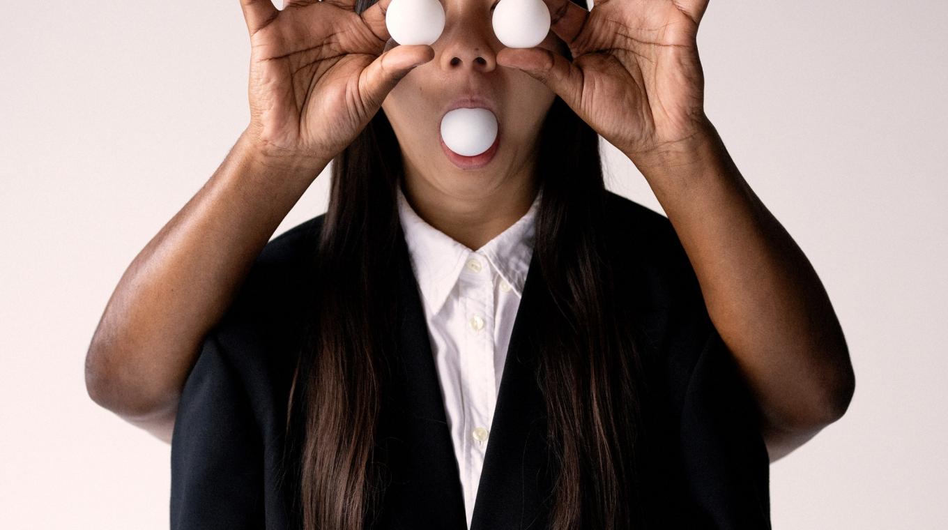 A woman with three ping pong balls two as eyes and one in her mouth