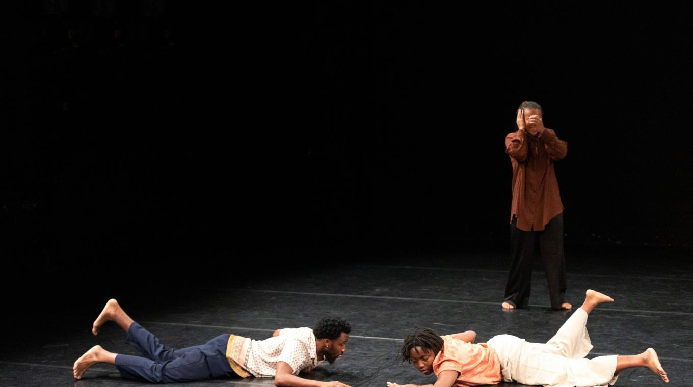 Two dancers lying down with one stood behind