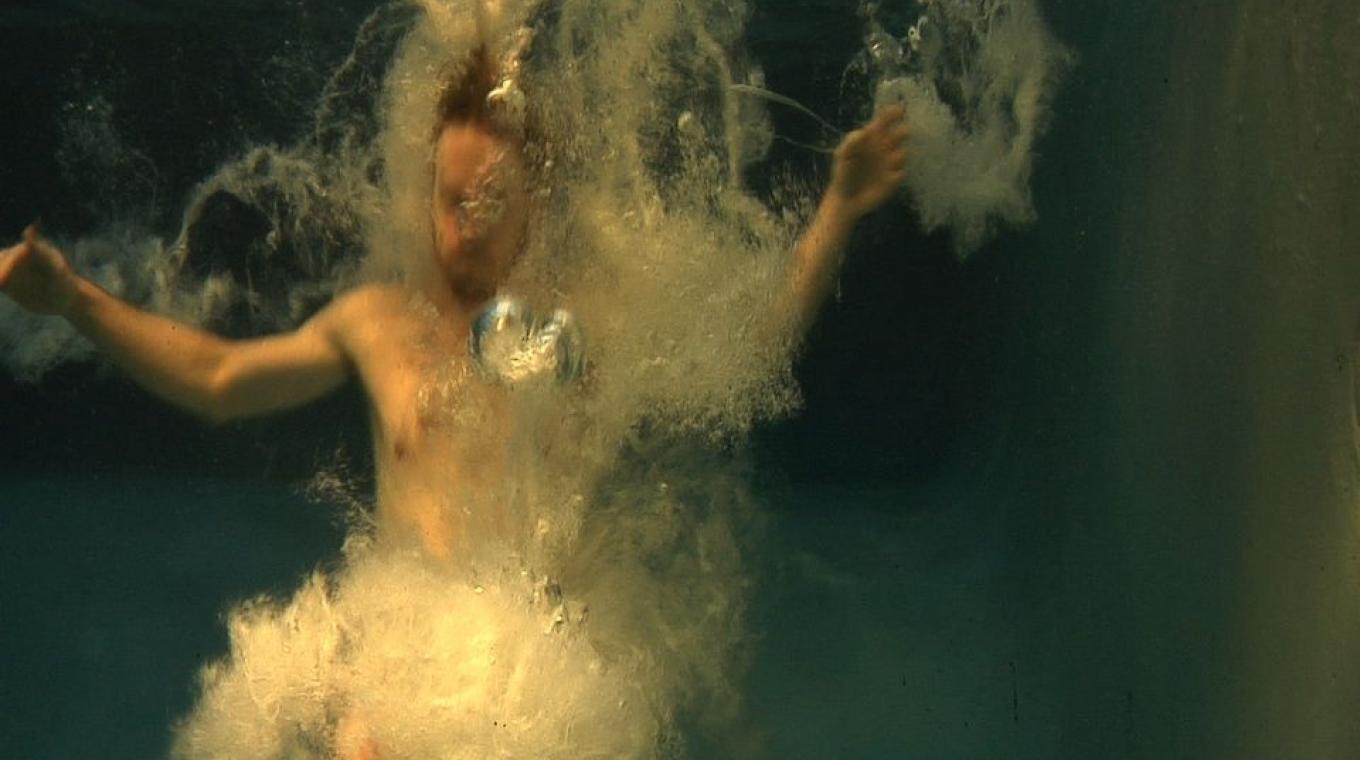 Underwater shot of a man sinking in water with bubbles around him