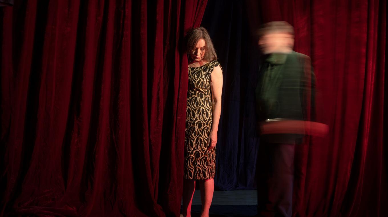 Two people standing by a stage curtain