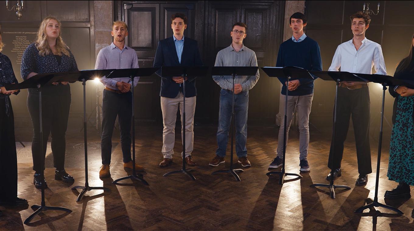 8 people in a choir singing in front of music stands