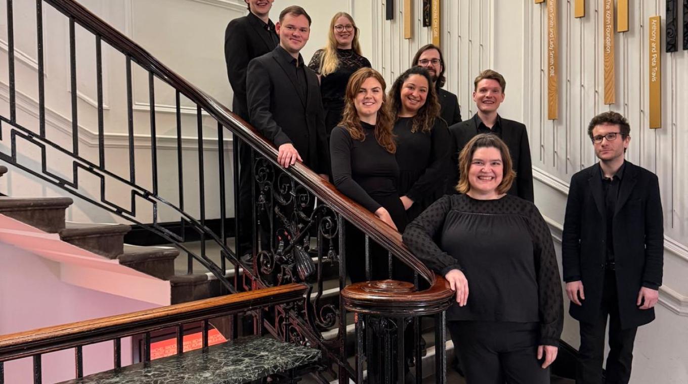 9 people wearing black standing on an ornate staircase