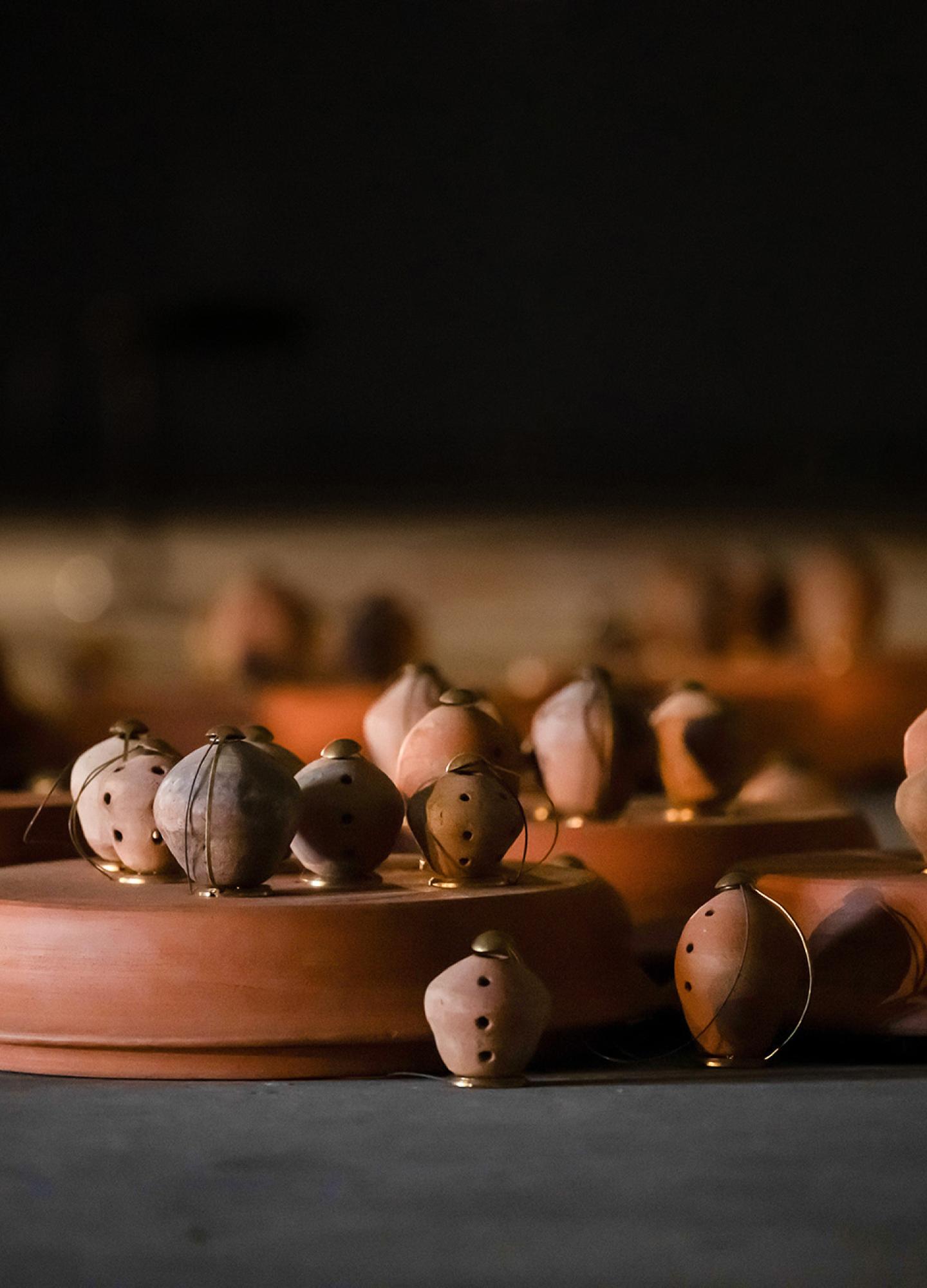 Around 30 small clay pots with holes in lit up from inside