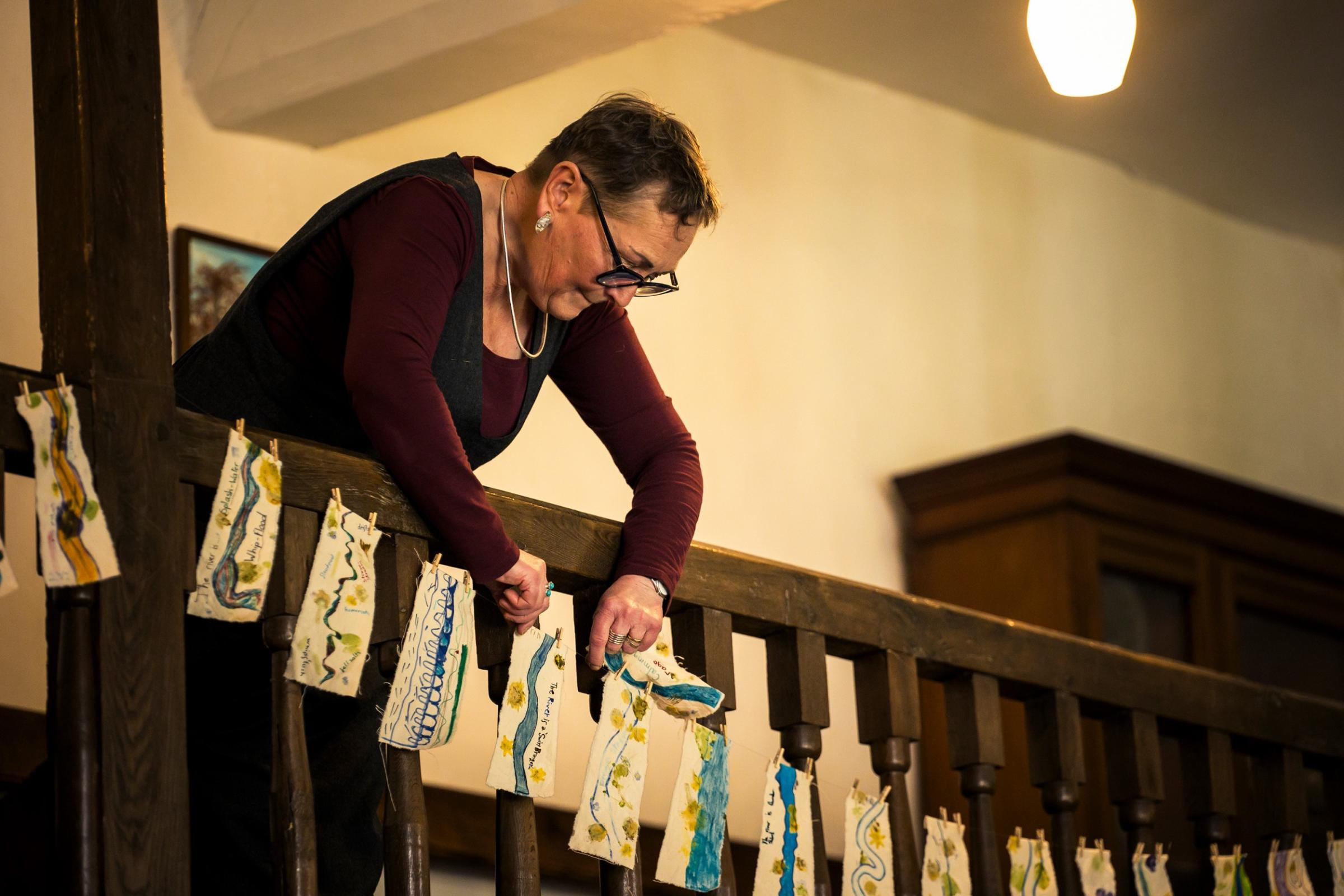 A woman hanging bookmarks on a balcony