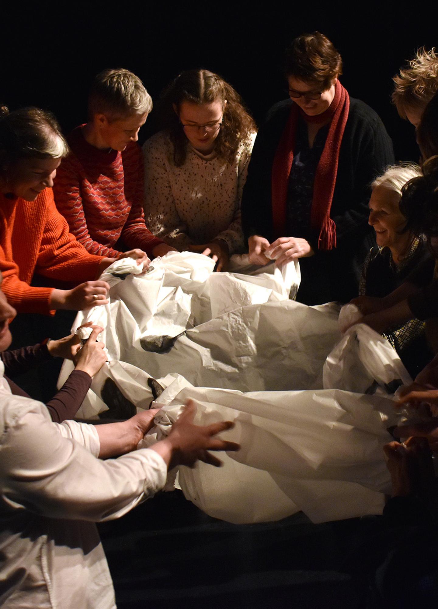 A group of people scrunching a white textile