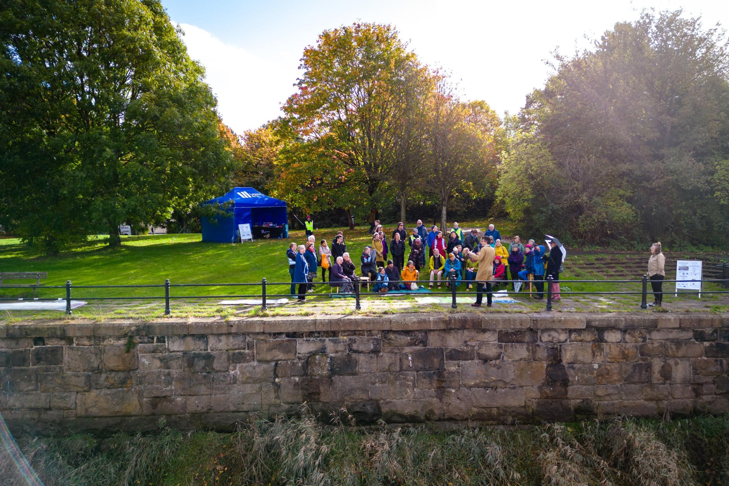 People watching a performance on the banks of a river