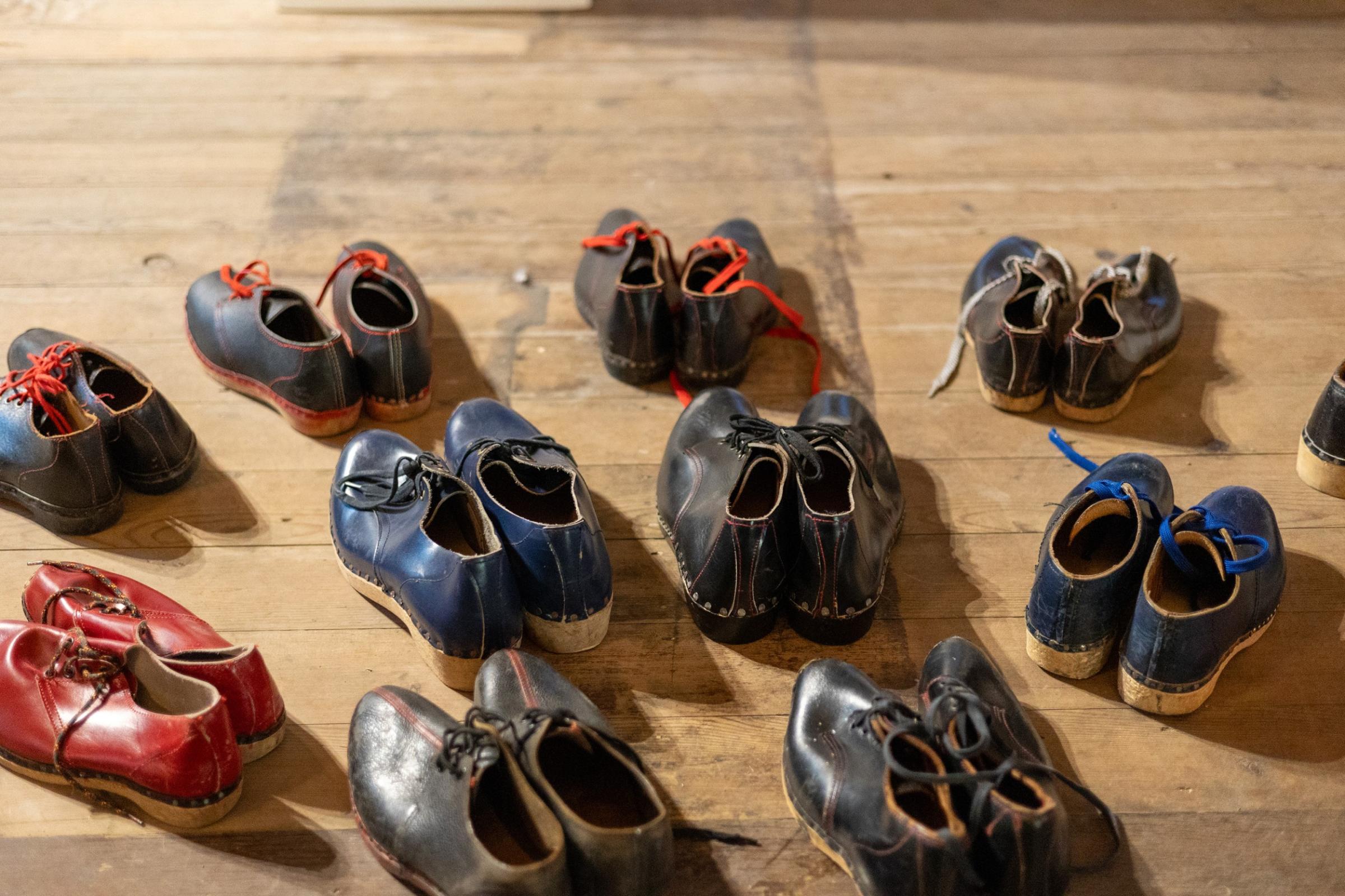 Ten pairs of clogs on a wooden floor