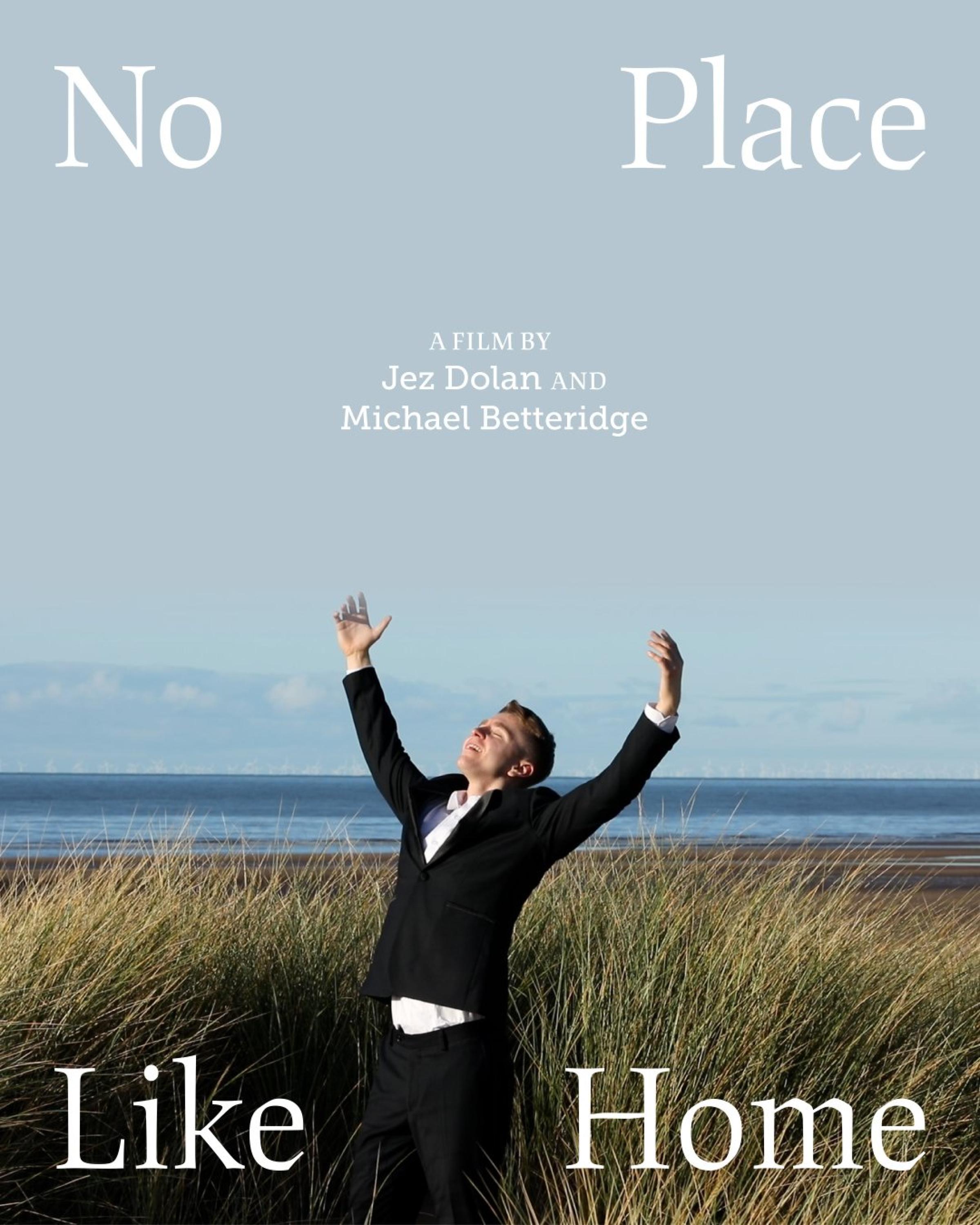 A man on a beach with the sea in the background with his arms raised above his head and text that reads 'No Place Like Home A film by Jez Dolan and Michael Betteridge'
