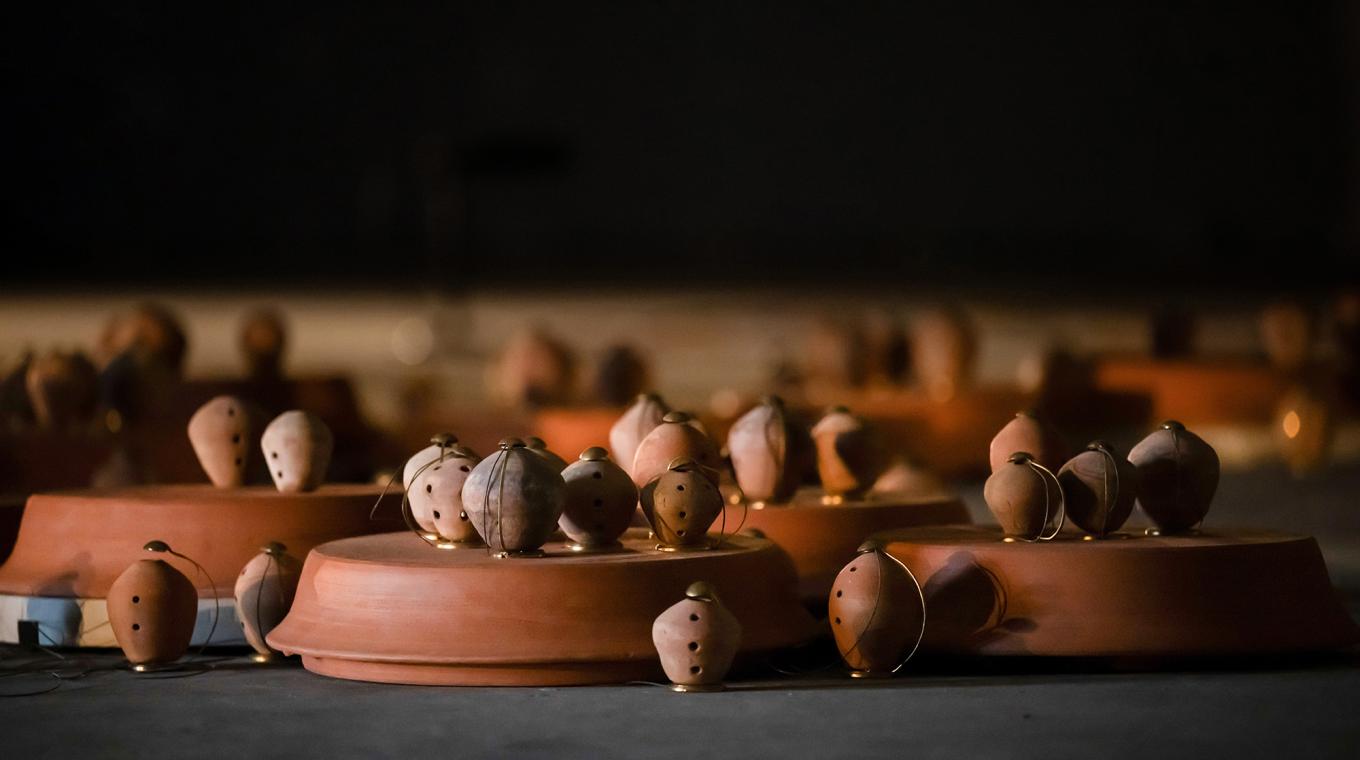 Around 30 small clay pots with holes in lit up from inside