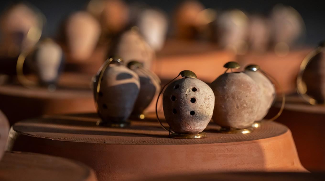 five clay pots with holes in and little metal attachments