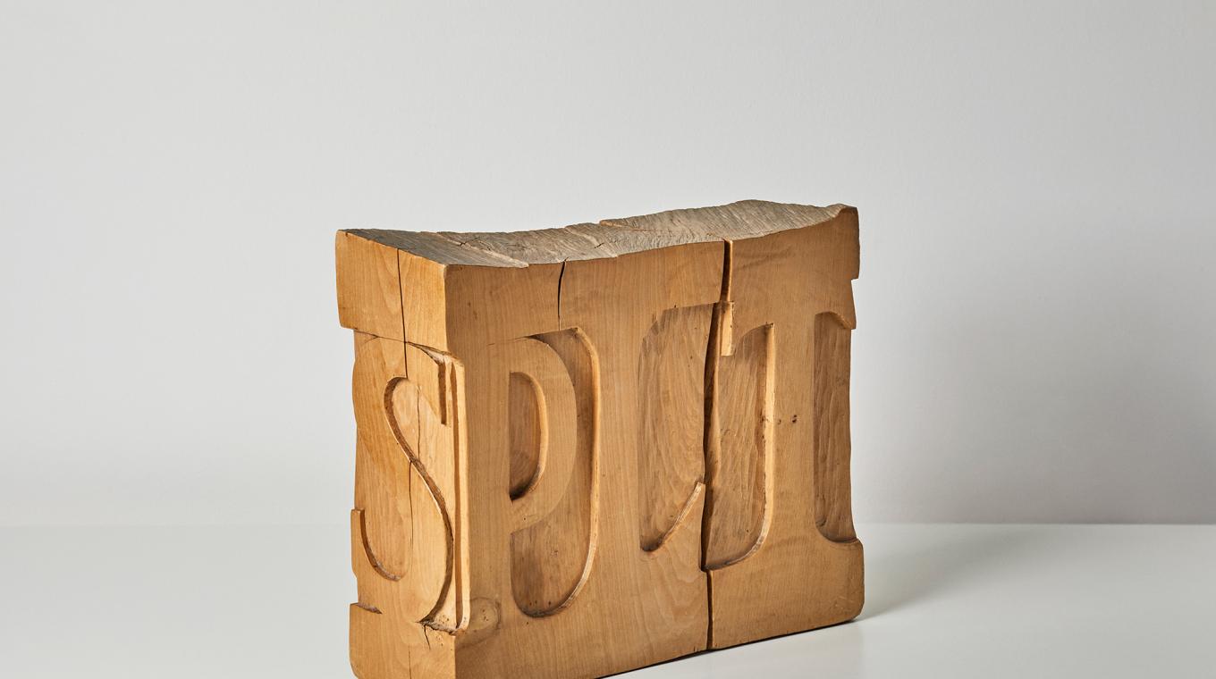 A wooden carving with the word "split' carved into it but the letter I is an actual split in the wood