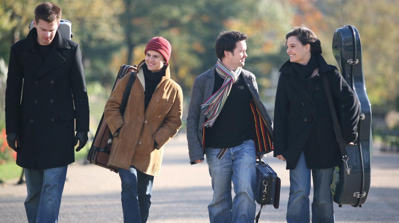 4 musicians walking on a wide path looking at each other