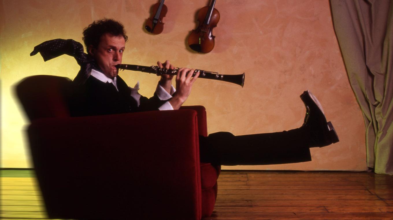 Comedian Rainer Hersch sat on a chair with his legs in the air