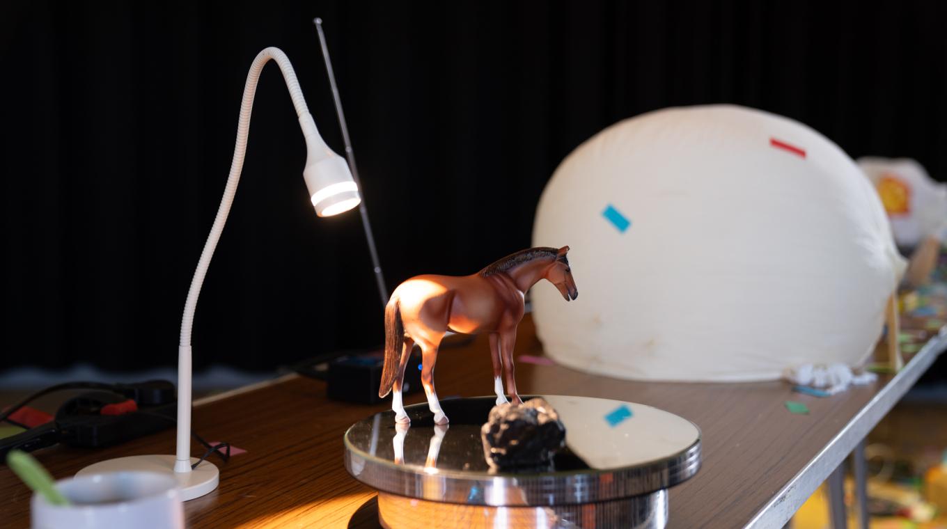A small horse figurine on a table with a little lamp shining on it