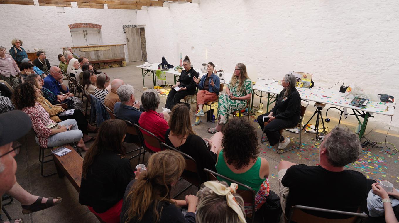 Four women sitting down facing an audience and talking to them
