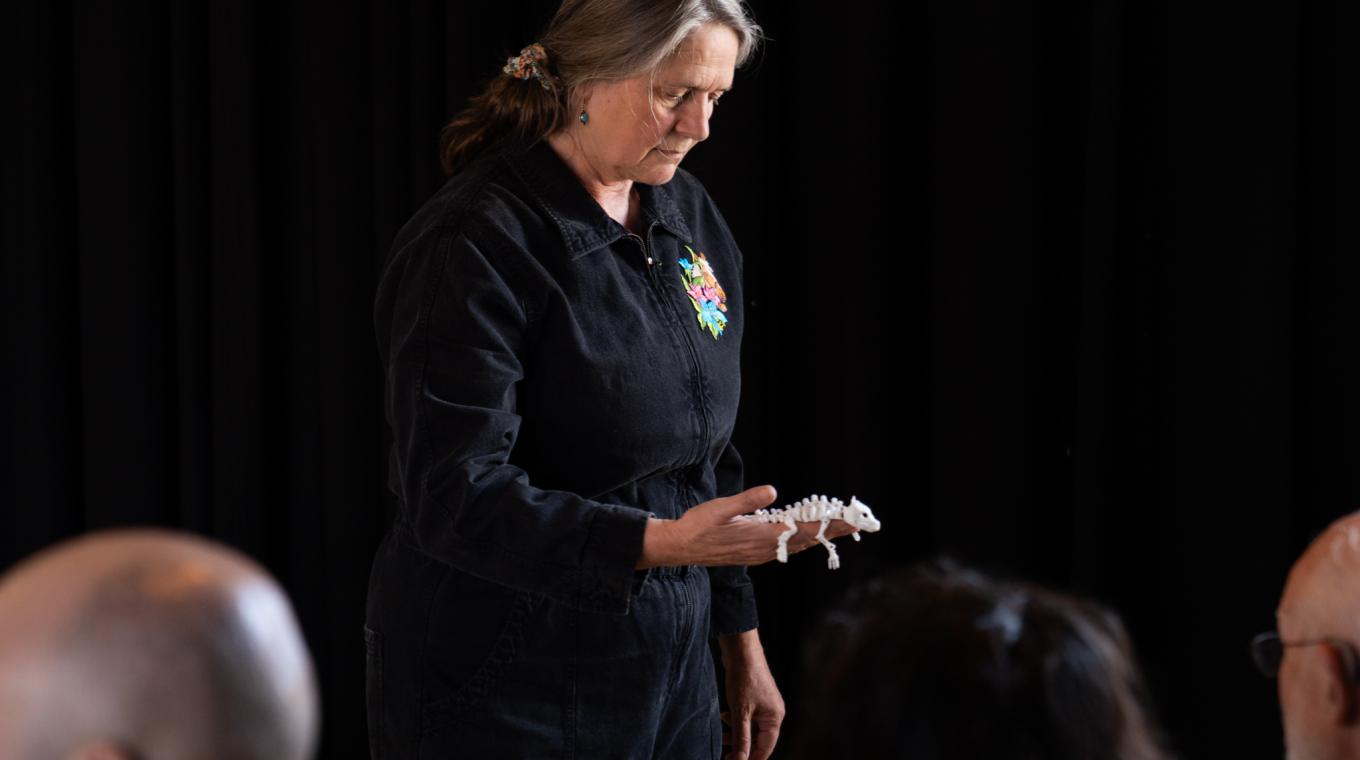 A woman holding a tiny skeleton of an animal