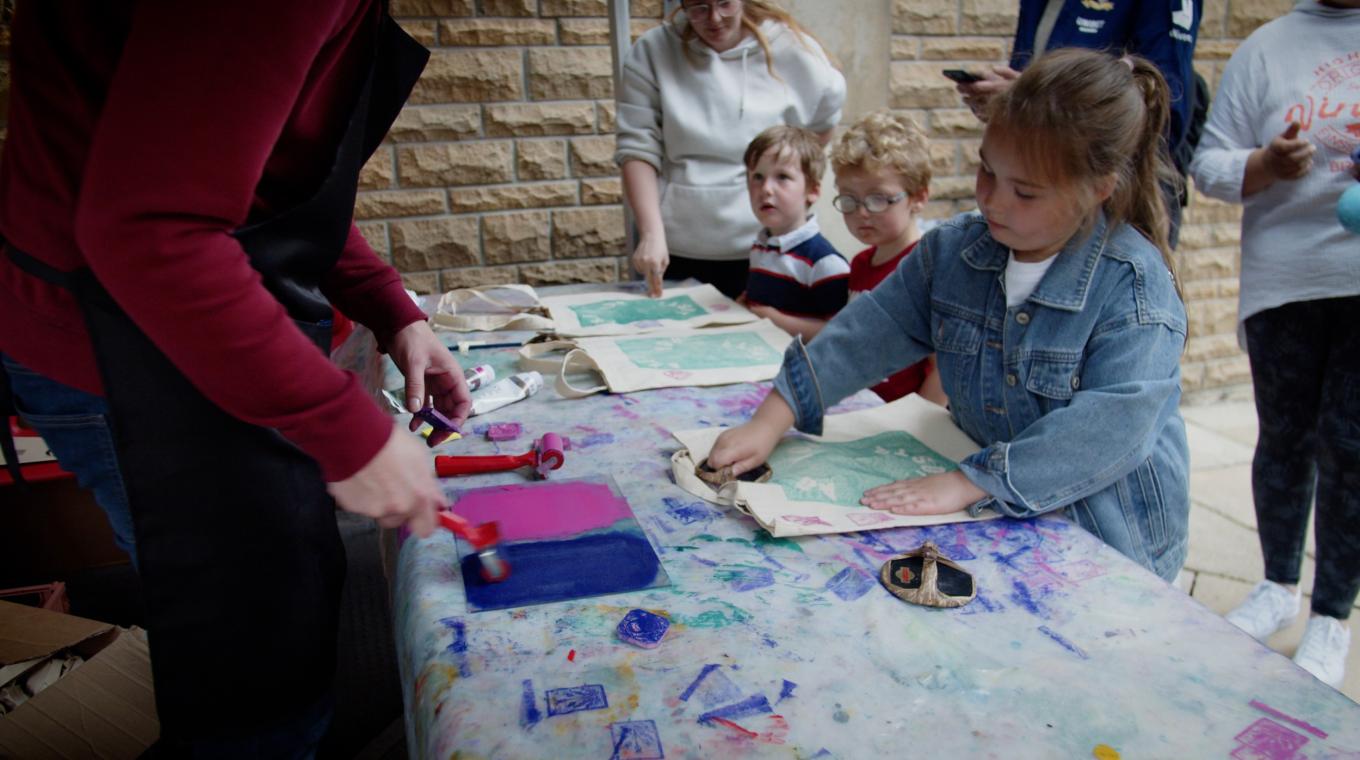 Children creating artwork on tote bags through screen printing
